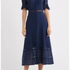 Navy blue button-down dress with lace panels, sheer lace bands at chest and hem, and short puff sleeves on a model wearing black sandals.