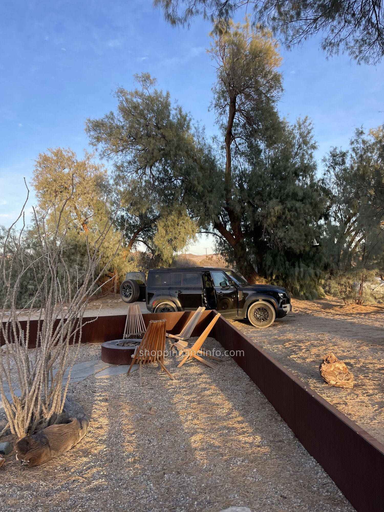 Our black Defender parked beside outdoor chairs and a fire pit at the desert rental