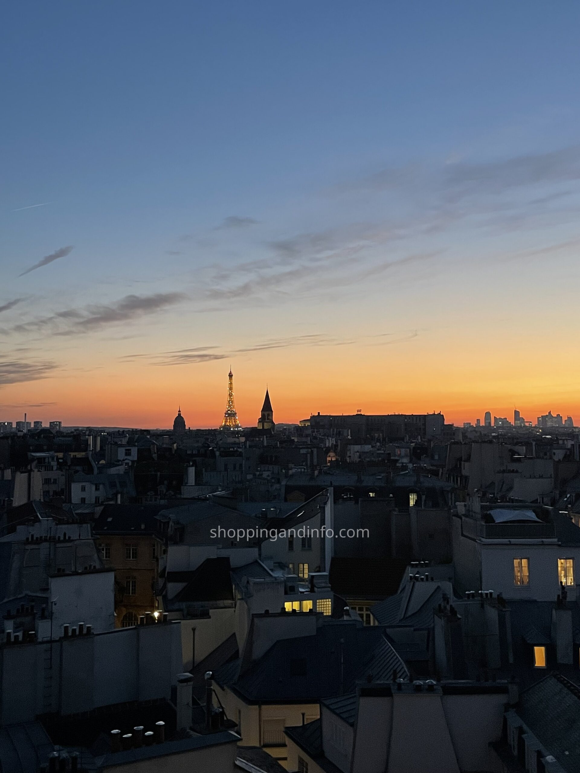 Eiffel Tower sparkling above Paris rooftops at dusk