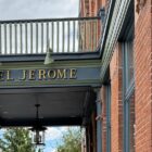 Hotel Jerome entrance sign beneath a balcony on the red-brick Aspen hotel.