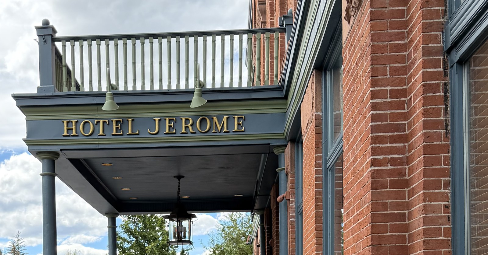Hotel Jerome entrance sign beneath a balcony on the red-brick Aspen hotel.